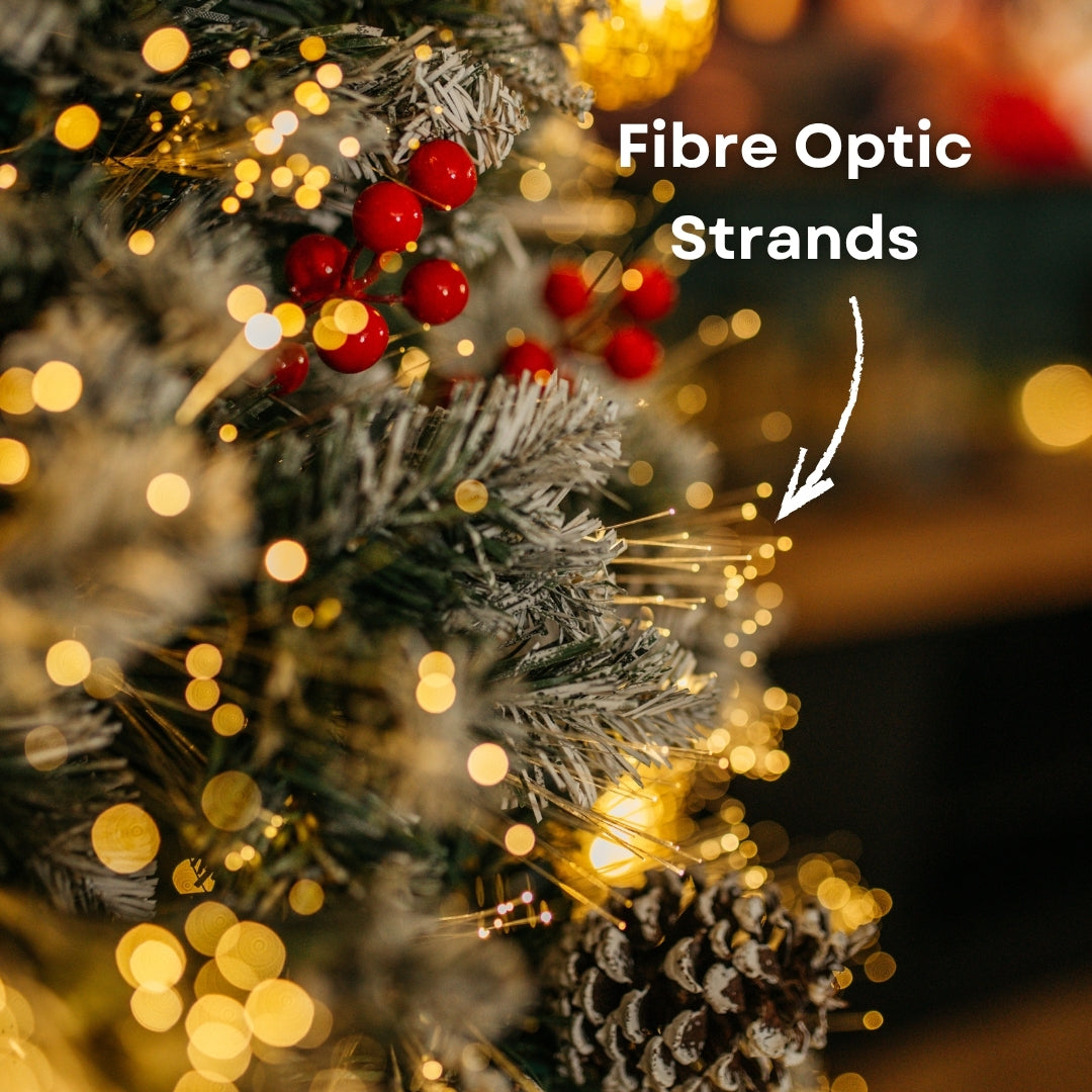Close-up of Christmas tree branch showing fibre optic strands glowing among frosted tips, red berries, and pine cones