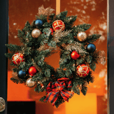 Christmas wreath with red, navy and gold ornaments hanging on a glass-panelled door