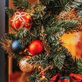 Close-up of red, navy and gold ornaments nestled in pine foliage on a Christmas wreath