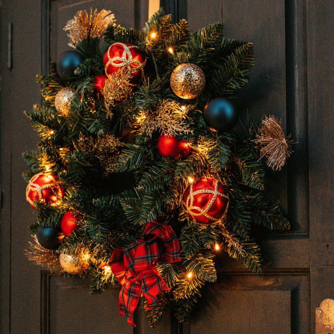 Christmas wreath with warm white LEDs hanging on a dark wooden panelled door