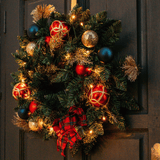 Christmas wreath with warm white LEDs hanging on a dark wooden panelled door