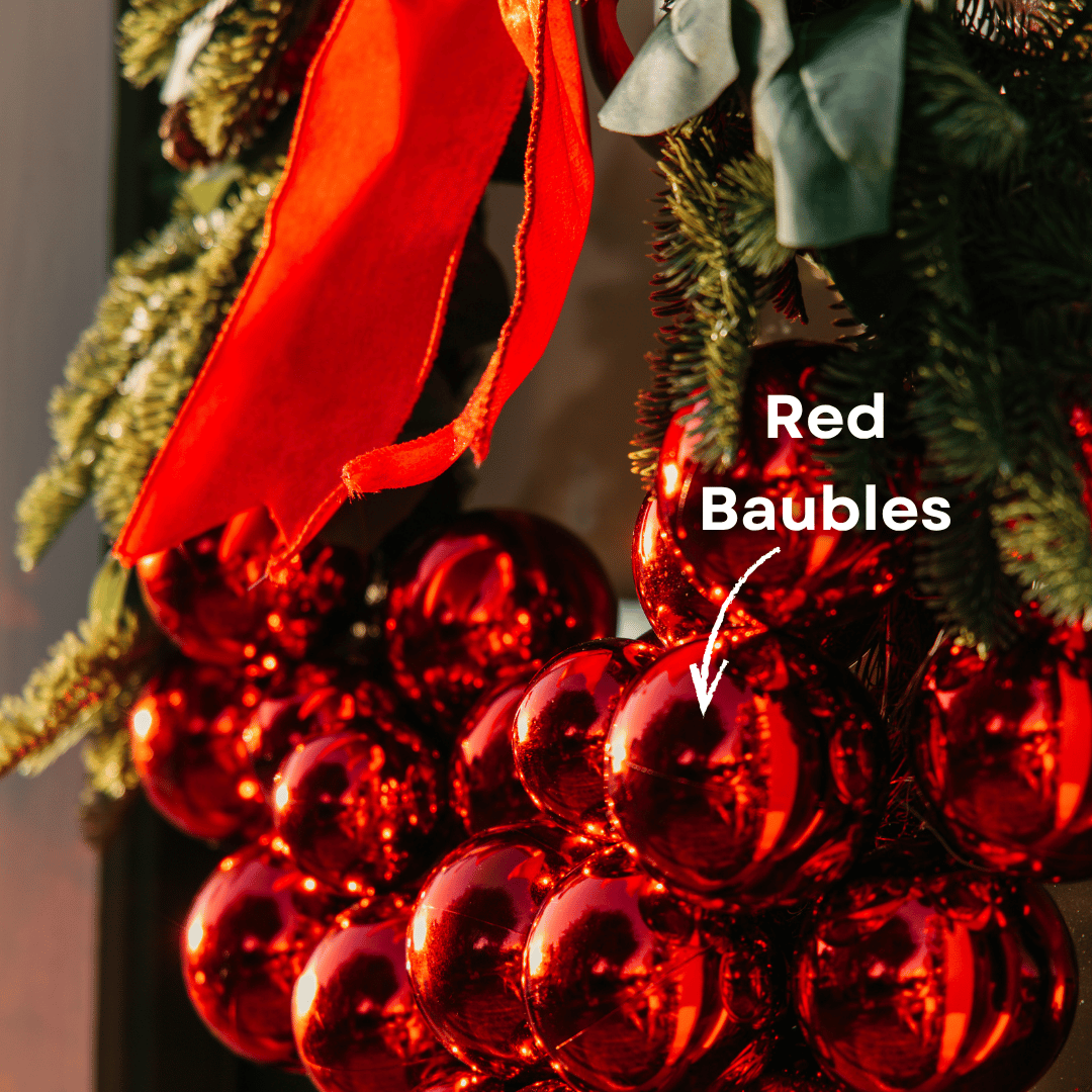 Close-up of red baubles on a luxury Christmas wreath beside a red velvet bow