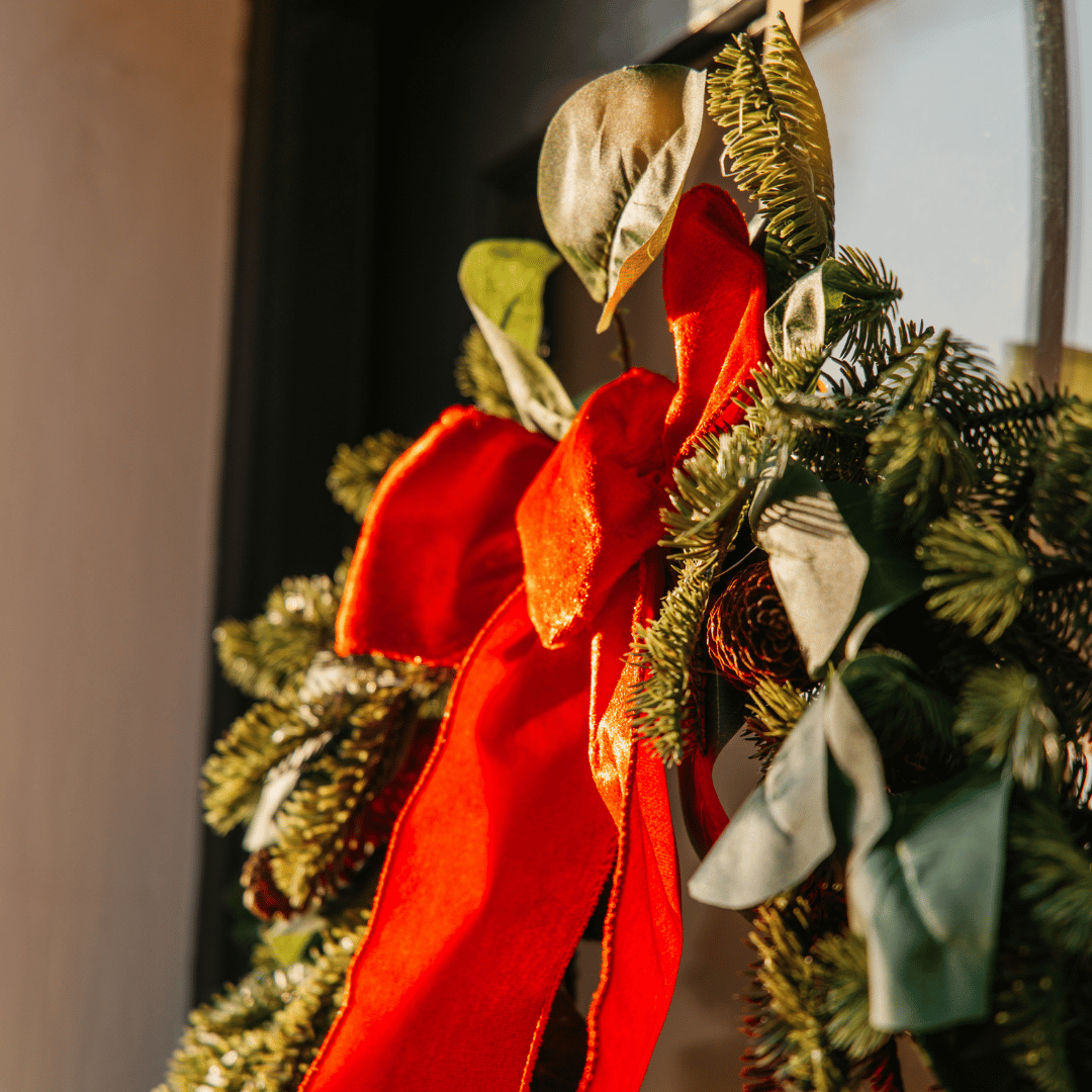 Close-up of a red velvet bow and eucalyptus leaves on a luxury Christmas wreath