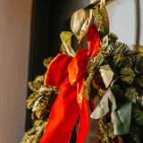 Close-up of a red velvet bow and eucalyptus leaves on a luxury Christmas wreath