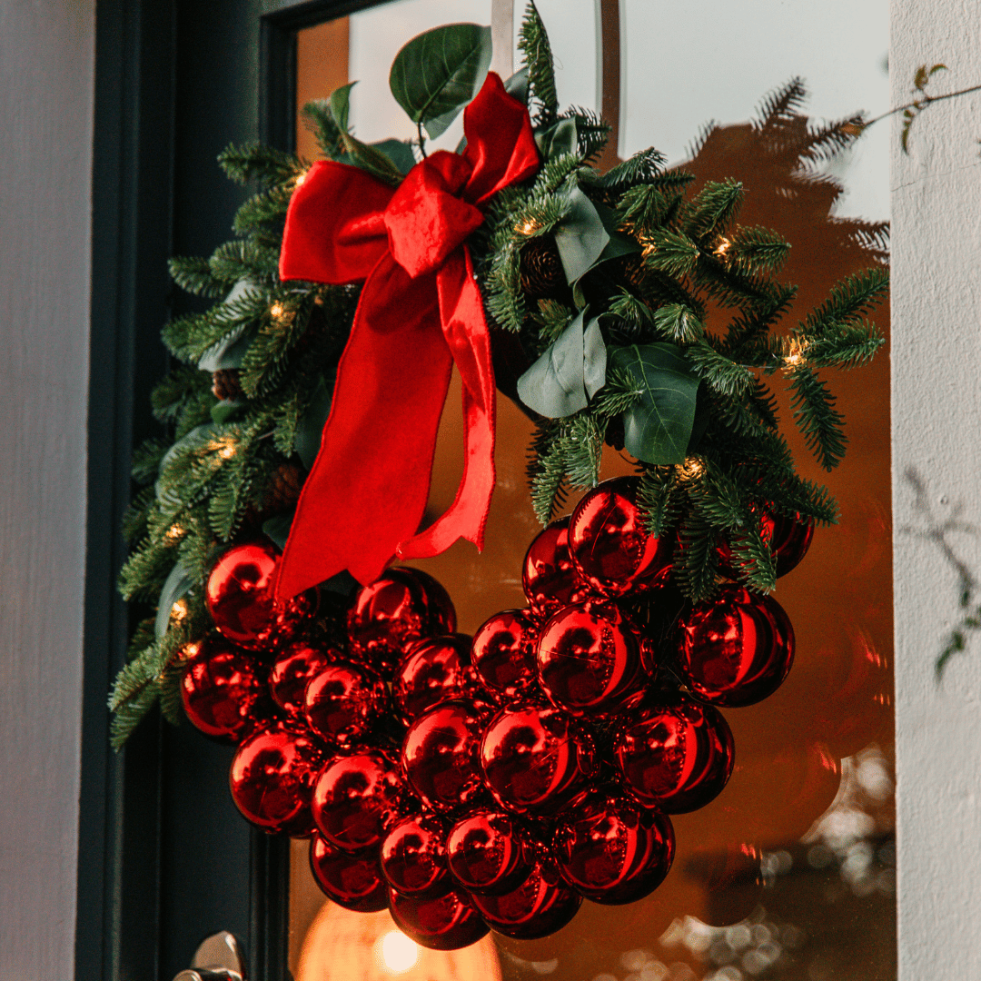 71cm luxury Christmas wreath with red bauble cluster and velvet bow hanging on a glass-panelled door