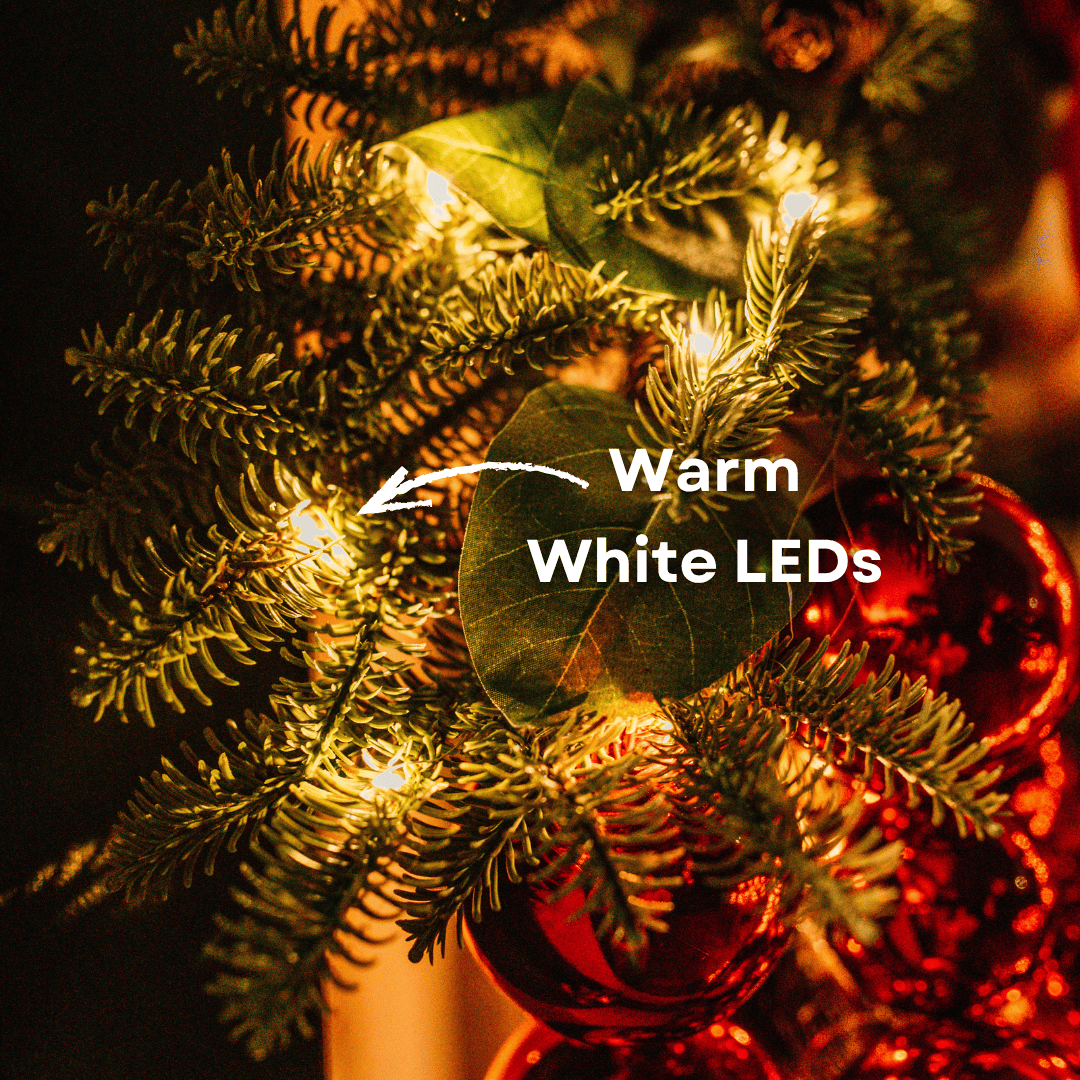 Close-up of a warm white LED light nestled in eucalyptus leaves and pine on a luxury Christmas wreath