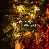 Close-up of a warm white LED light nestled in eucalyptus leaves and pine on a luxury Christmas wreath