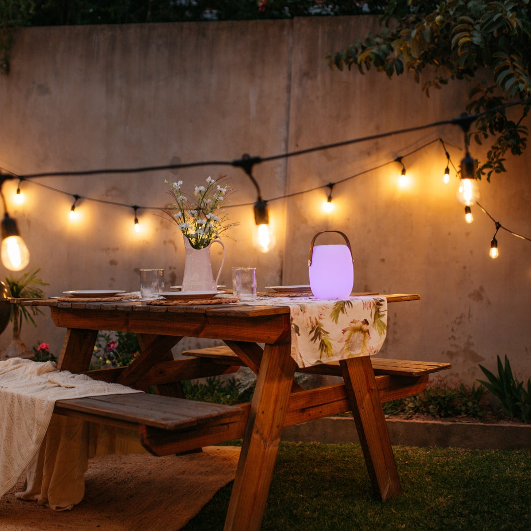 Bluetooth Speaker Lantern with wooden handle creating warm ambient glow on an outdoor table during a South African evening gathering