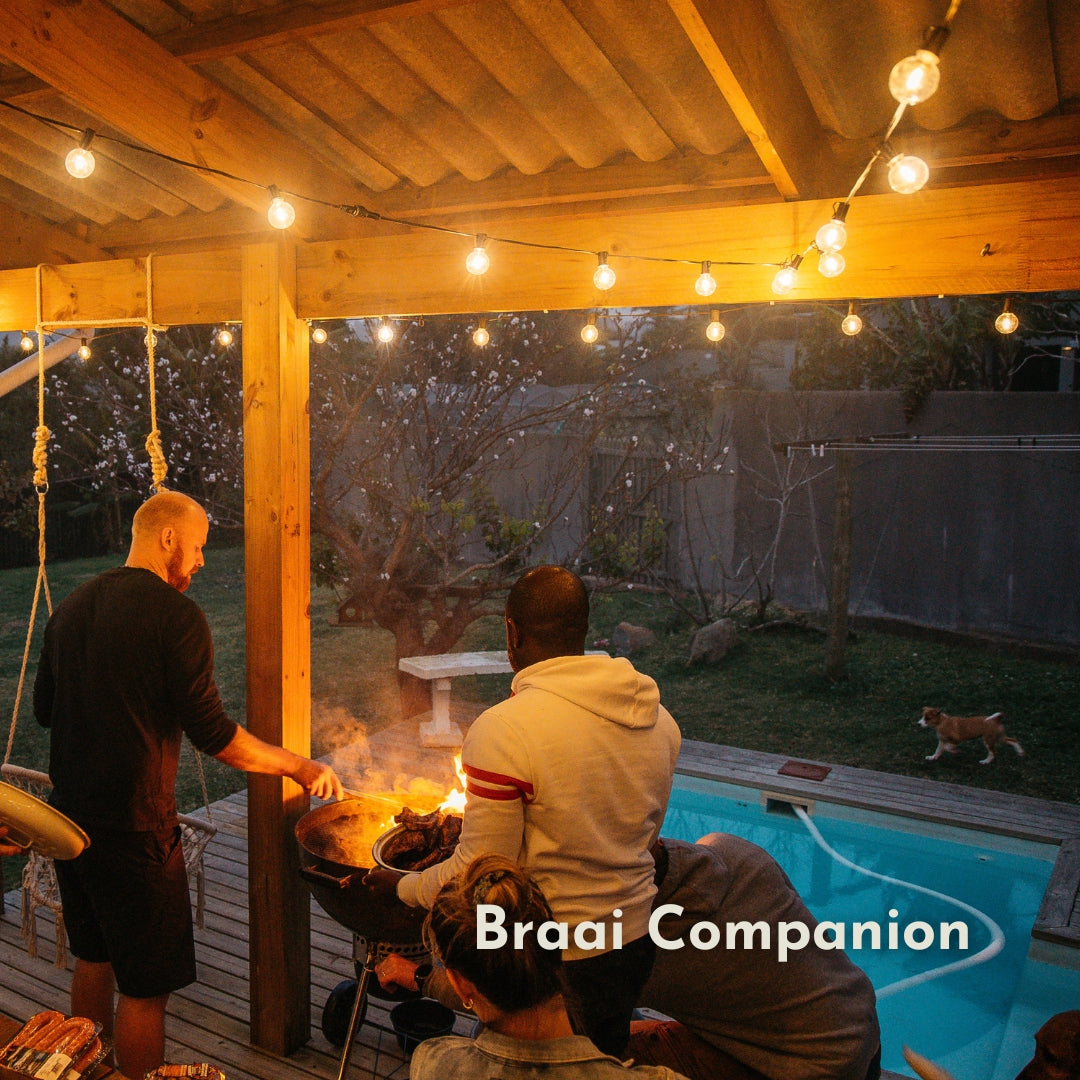 Classic String Lights with 25 warm white G40 globe bulbs strung across a South African outdoor braai area creating a warm golden glow at dusk with friends and family gathering