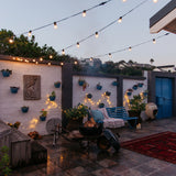 Classic String Lights Pro strung across a courtyard with a fire pit and fairy lights creating ambience.