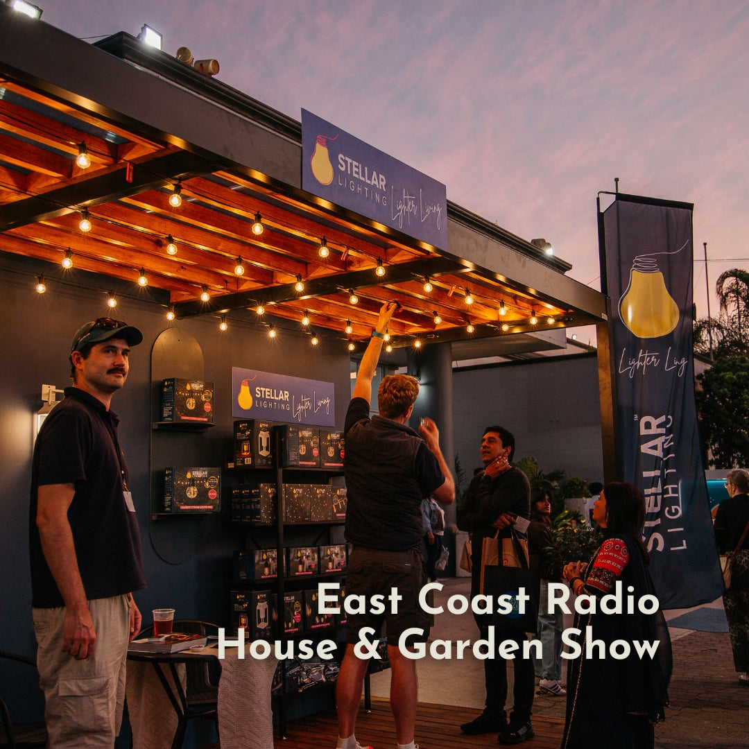 Stellar Lighting stand at the East Coast Radio House and Garden Show at dusk showing Classic String Lights Pro strung above the display with branding banners and product boxes