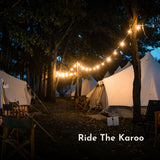 Classic string lights strung between trees across a glamping site with canvas bell tents at Ride The Karoo at night