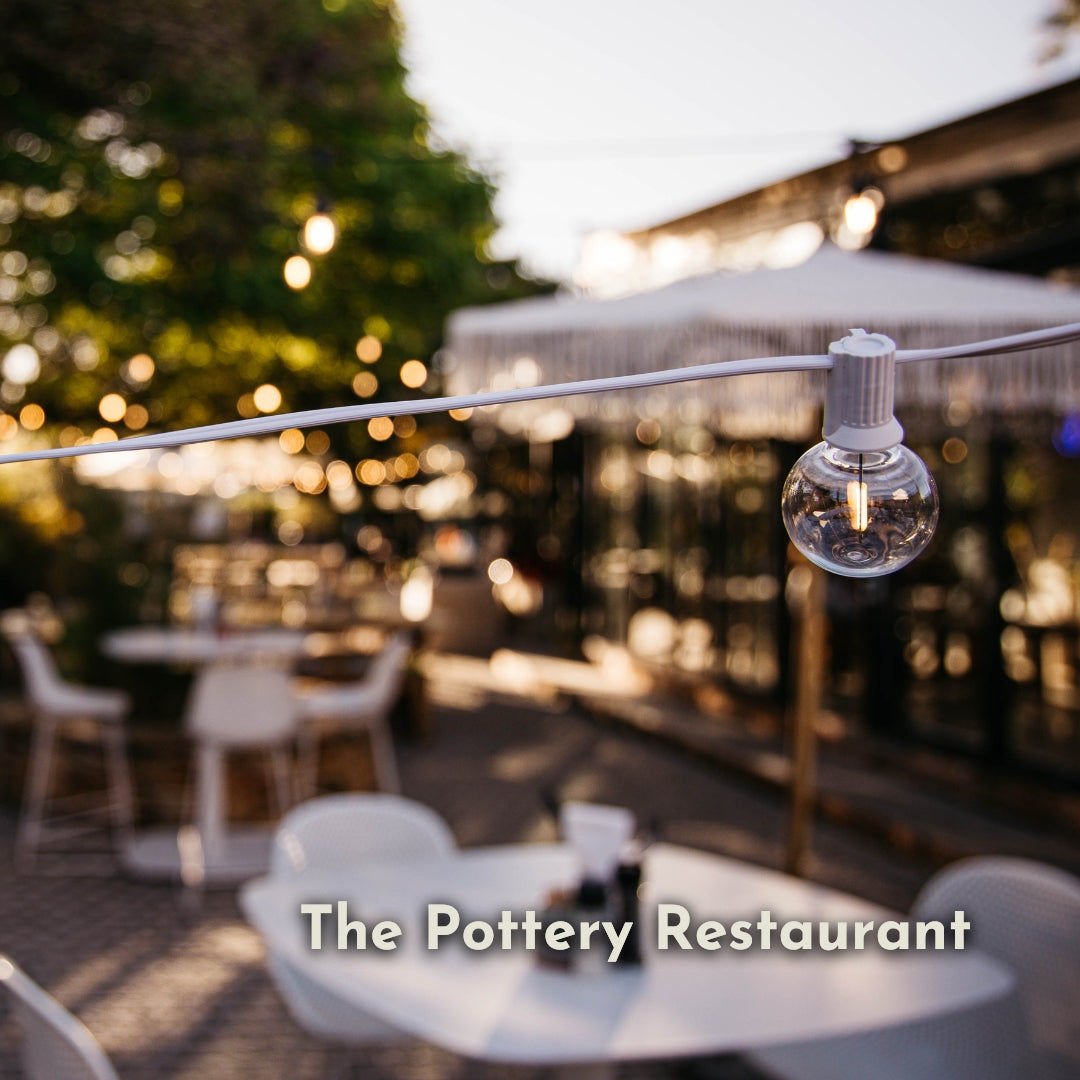 Classic string lights with G40 globe bulbs on white cable strung across The Pottery Restaurant outdoor terrace at sunset