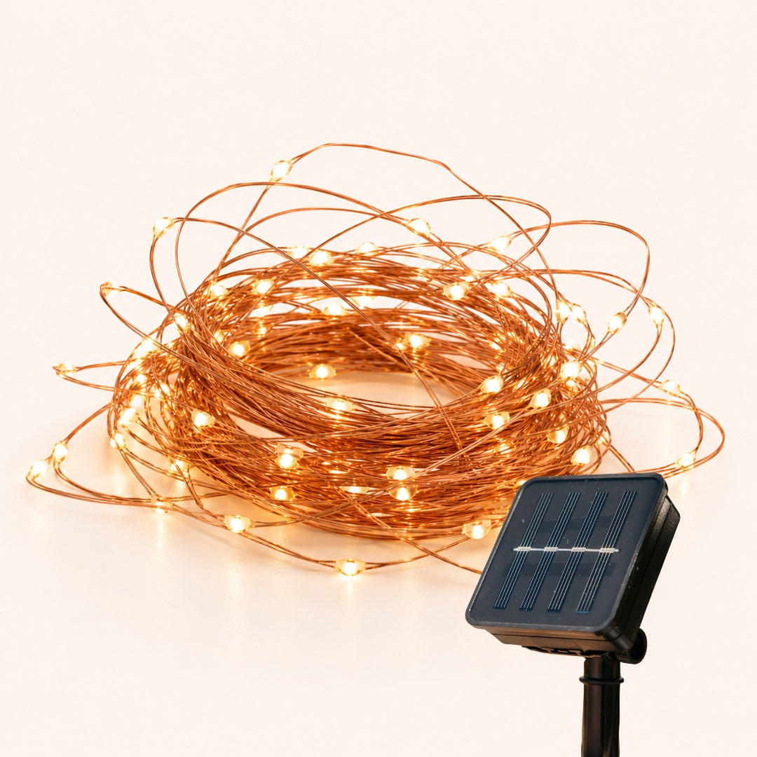 Coiled copper fairy lights with a solar panel on a white background