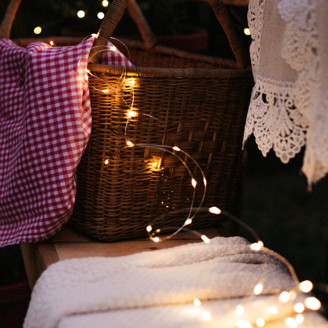 Wicker basket with copper fairy lights and checkered cloth on a wooden surface
