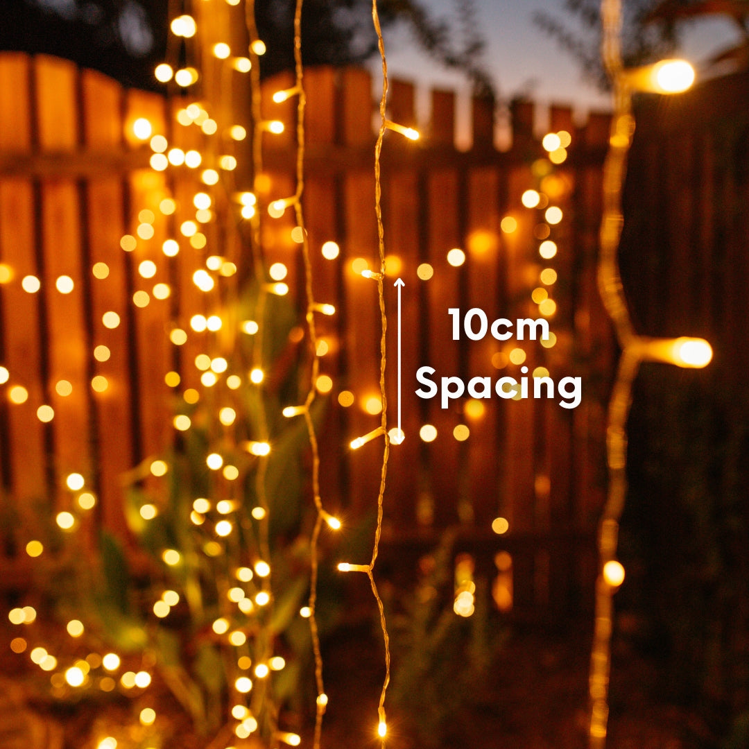 Curtain fairy lights with 10cm spacing measurement against a wooden fence background