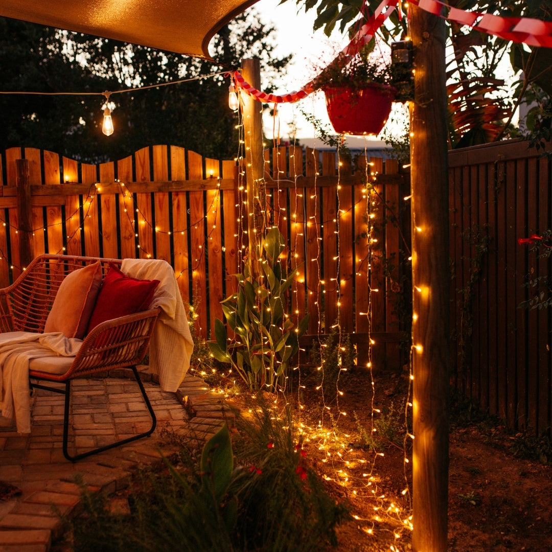 Backyard with curtain fairy lights, outdoor furniture, and decorative elements.