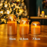 Set of three domed gold glass flameless LED candles on a wooden table showing graduated heights of 15cm, 12.5cm, and 7.5cm with Christmas bokeh background