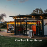 Outdoor setting of KamBati River Resort Pizza Area with a building and people sitting under a canopy.