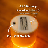 Close-up of flameless candle with a 2AA battery requirement and on/off switch on a warm background.