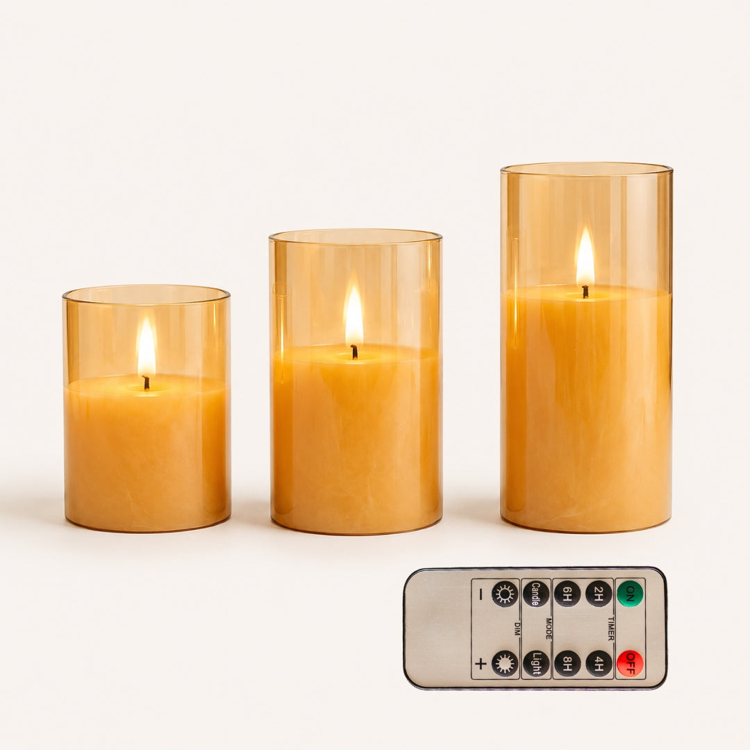 Three lit candles in glass holders with a remote control on a white background