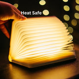 Hand opening foldable LED book light glowing with warm white light with heat safe callout