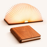 Foldable LED book light shown open and glowing and closed in walnut wood finish on white background