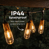 String of gold drop string lights with IP44 splashproof text on a dark background