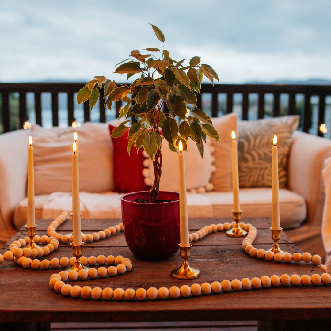 Ivory flameless taper candles glowing on a coffee table creating warm ambient light in an evening setting