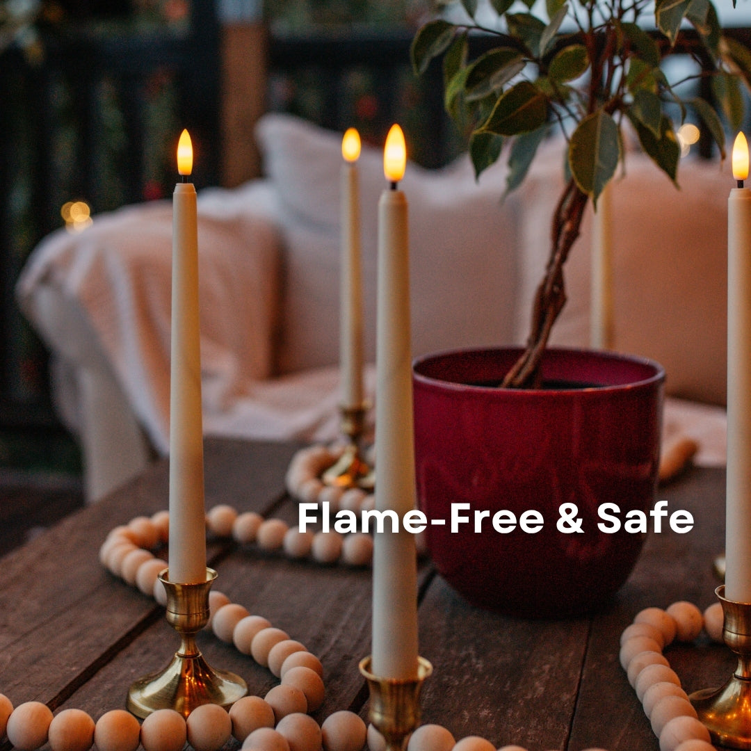 Ivory flameless taper candles in brass candlestick holders on a wooden table with bead garland and plant showing flame-free and safe callout