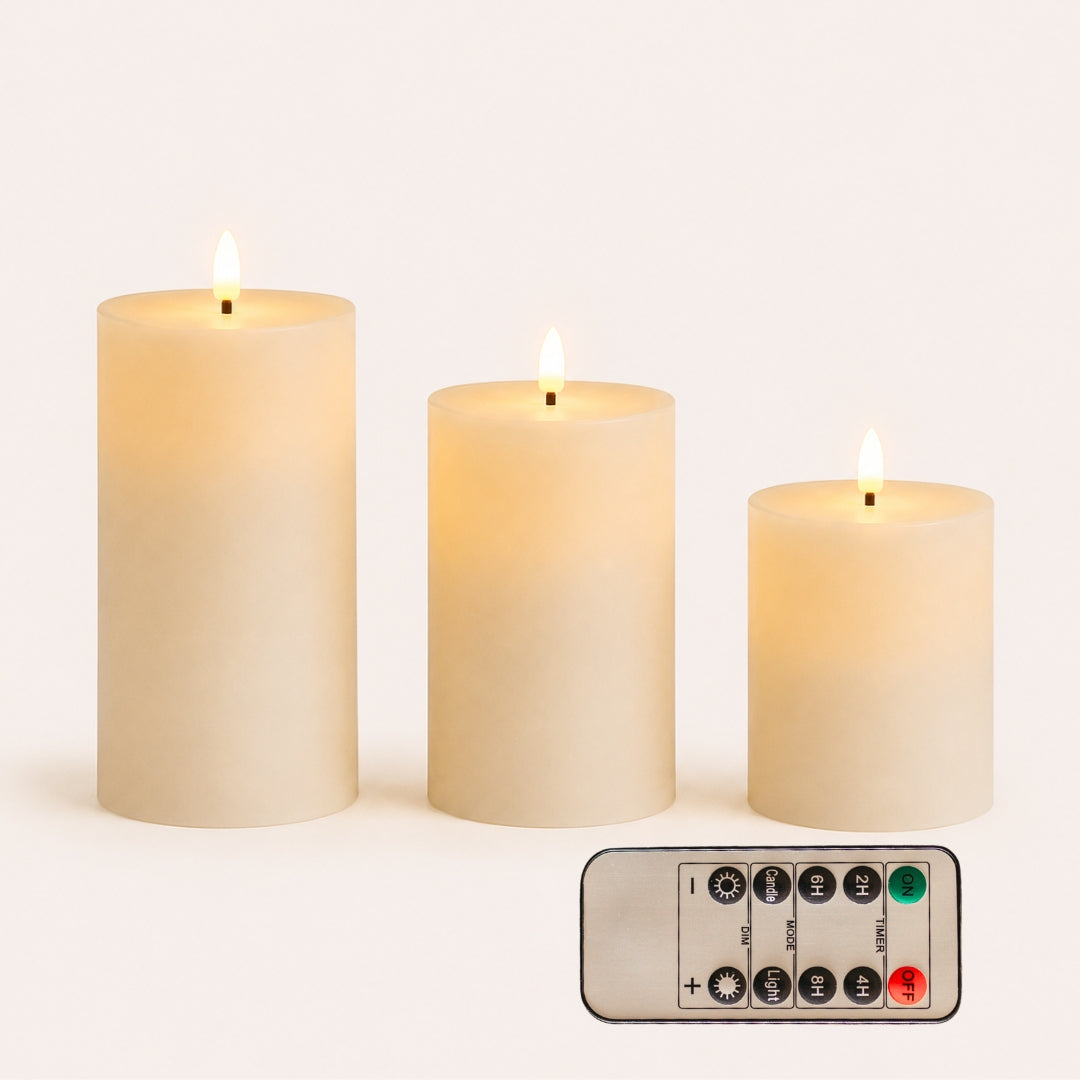 Set of three smooth white real wax flameless LED pillar candles in graduated heights with remote control on white background