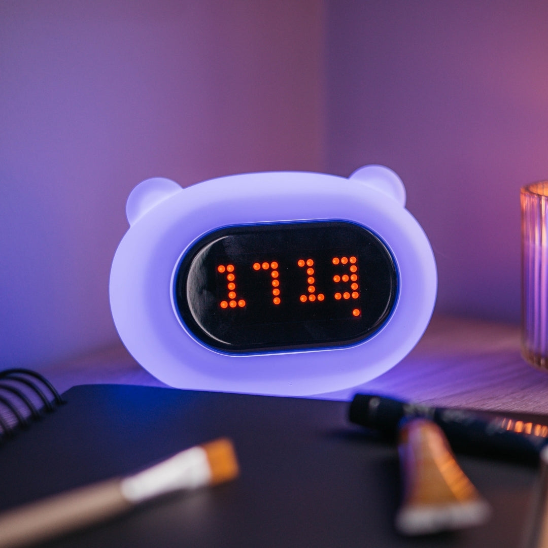 Lightie Clock bear silicone kids night light glowing in a colour changing mode on a bedside surface