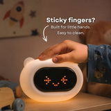 Damp cloth wiping the surface of the Lightie Clock bear kids night light with wipe clean callout showing easy cleaning for sticky fingers