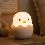 Lightie Egg silicone kids night light glowing warm white on a bedside table in a softly lit children's room