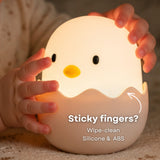 Damp cloth wiping the surface of the Lightie Egg silicone kids night light with wipe clean callout showing easy cleaning for sticky fingers