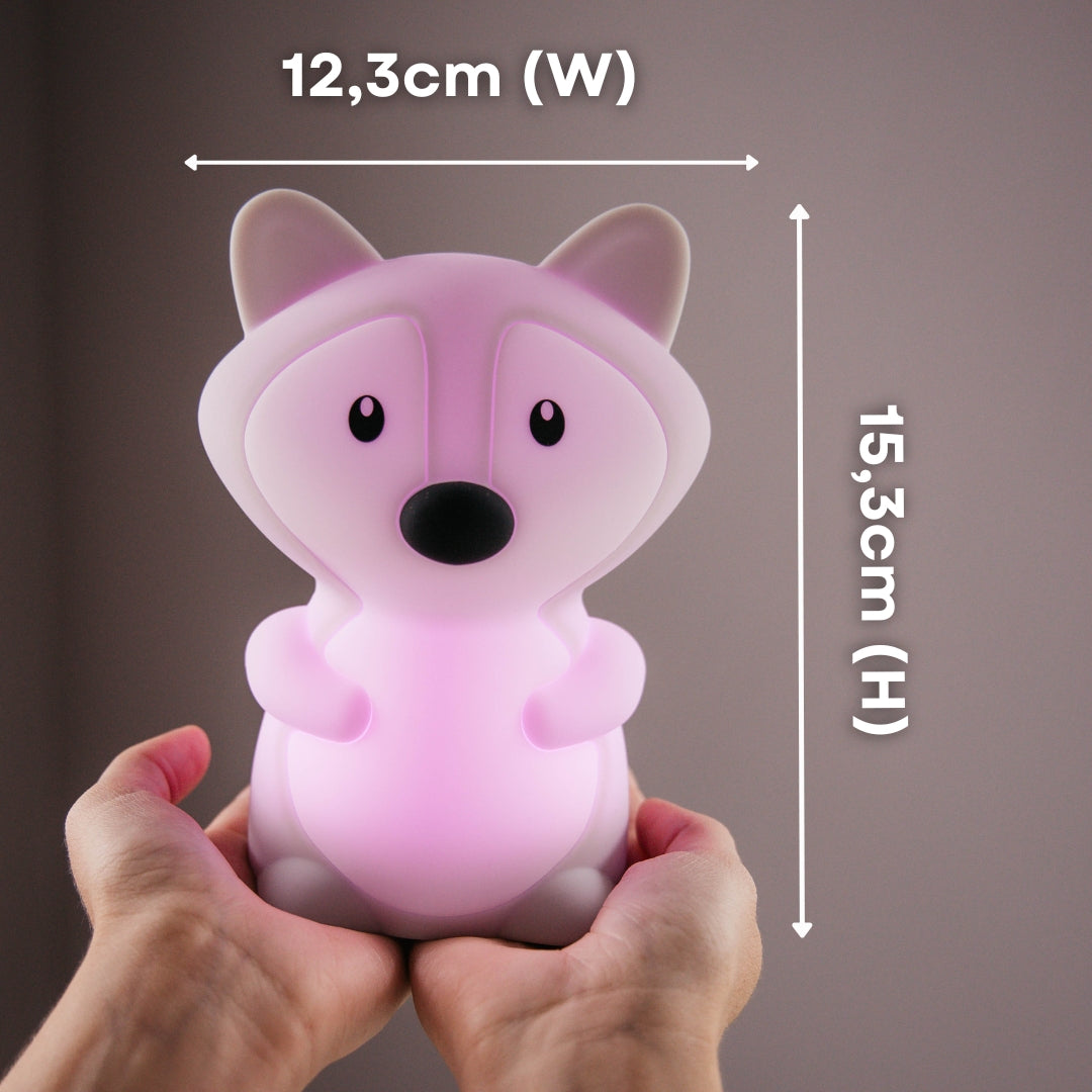 Hands holding the Lightie Fox night light glowing pink with dimension callouts showing 12.3cm width and 15.3cm height