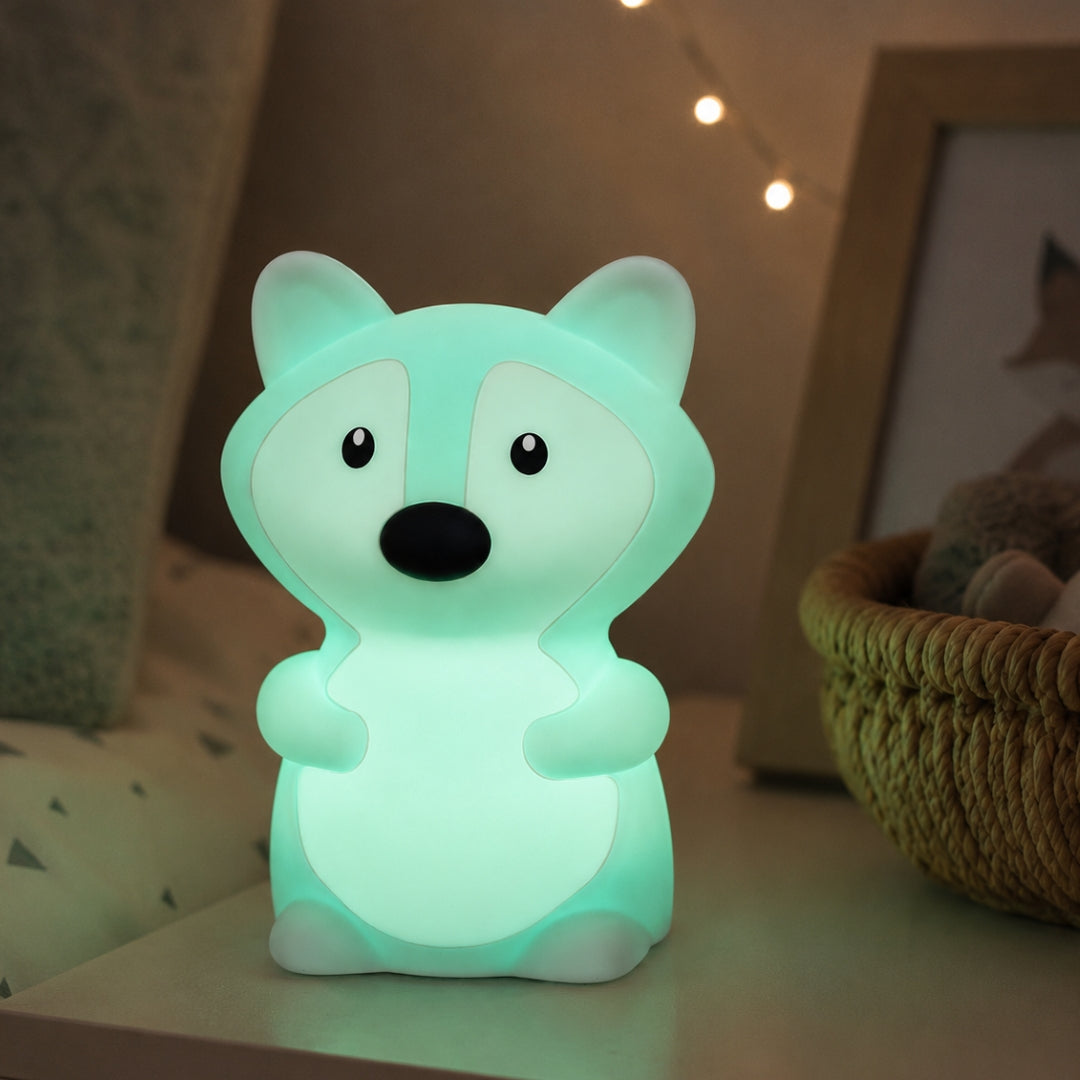 Lightie Fox silicone kids night light glowing teal on a bedside table in a softly lit children's room with fairy lights in the background