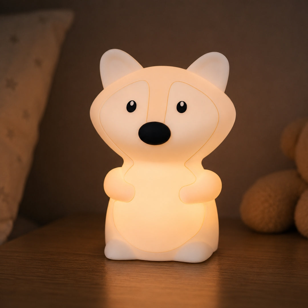 Lightie Fox silicone kids night light glowing warm white on a wooden bedside surface with cushions in the background