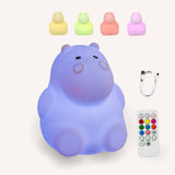 Lightie Hippo silicone night light shown in four colour modes including warm white, blue, pink, and purple with USB charging cable and remote control included