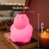 Hands holding the Lightie Hippo night light glowing pink with dimension callouts showing 12.3cm width and 15.3cm height