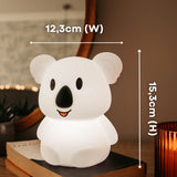 Hands holding the Lightie Koala night light glowing pink with dimension callouts showing 12.3cm width and 15.3cm height