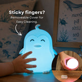 Child's hand touching the Lightie Penguin  night light glowing blue with sticky fingers and removable cover for easy cleaning callout and inset showing detached cover