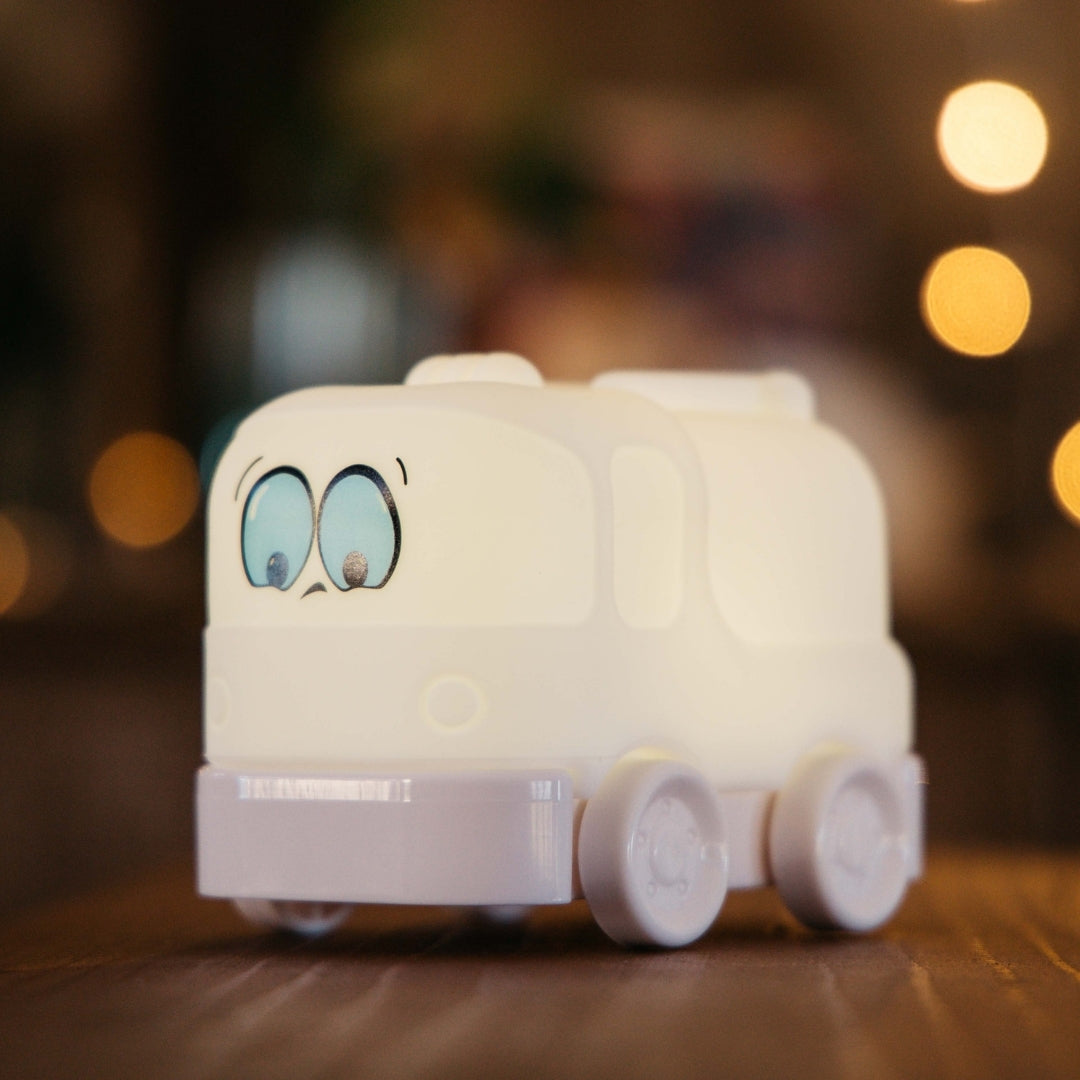 Lightie Truck silicone kids night light glowing warm white on a wooden bedside surface