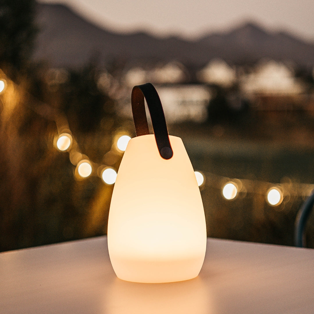 Rechargeable RGB camping lantern glowing with warm white light in an outdoor lifestyle setting