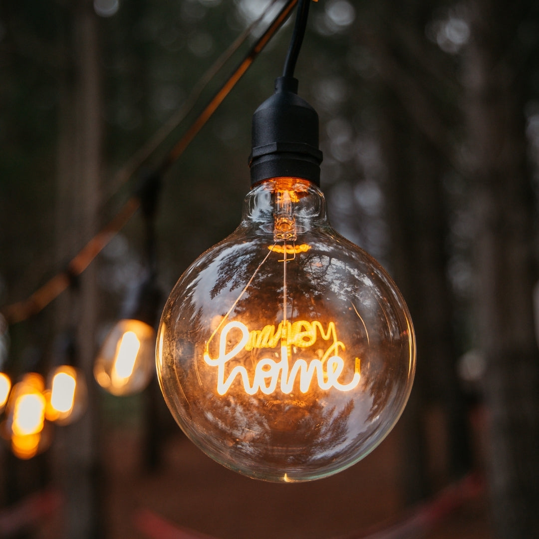 G125 globe LED bulb with warm white HOME filament glowing in an interior pendant fitting