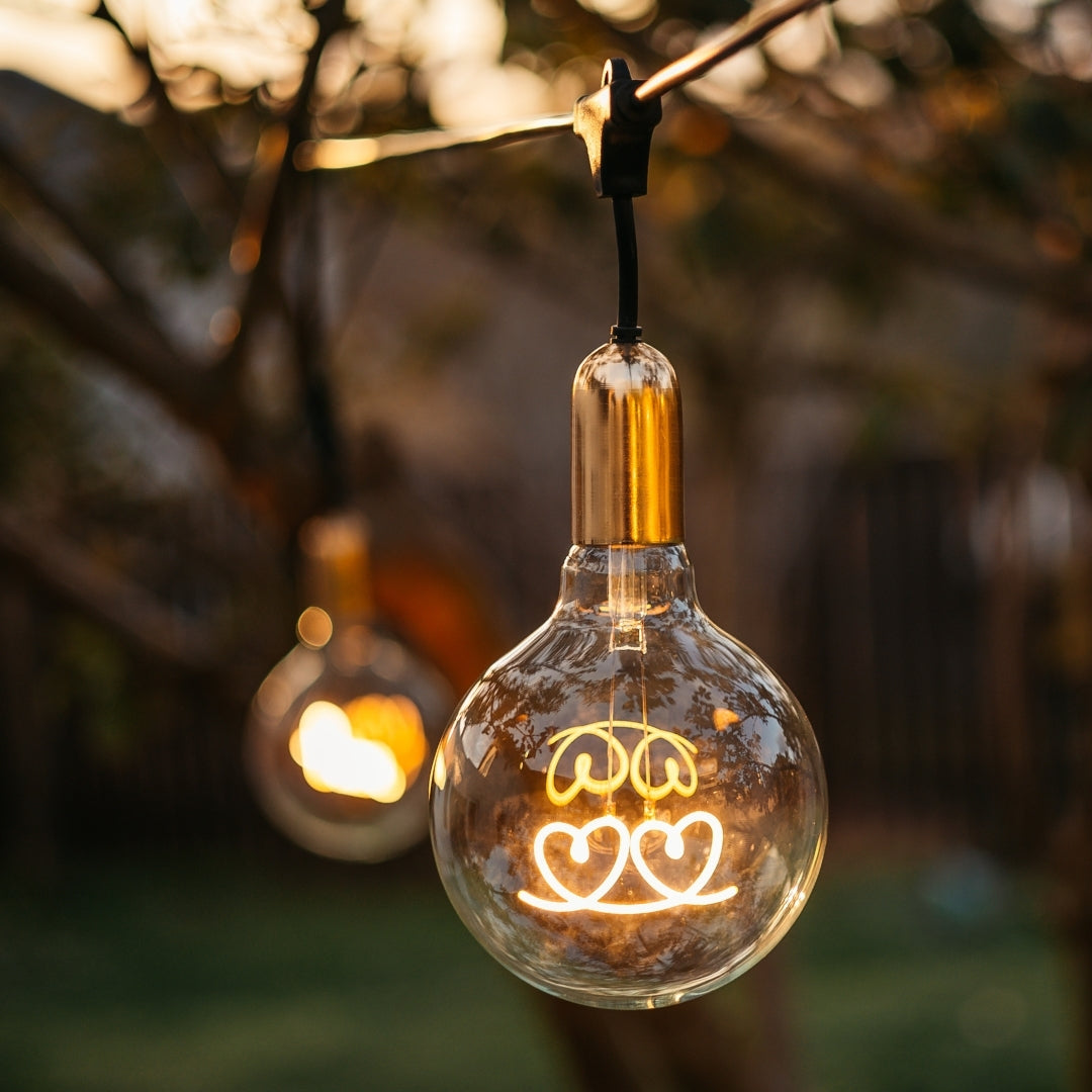 G125 globe LED bulb with warm white hearts filament glowing softly in an interior pendant fitting