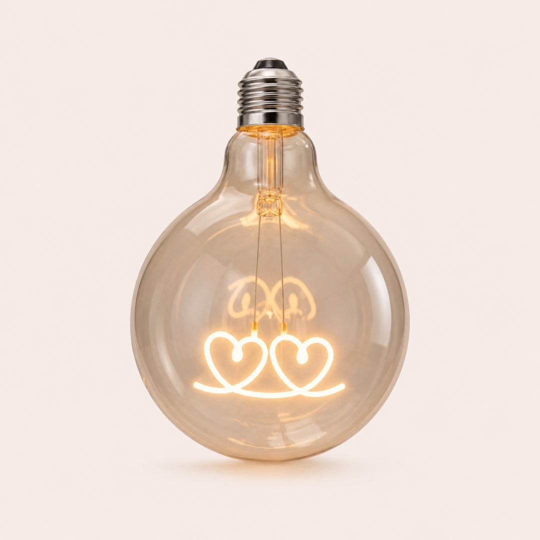 Single G125 globe LED bulb with two heart shaped filament detail and clear glass on a light background