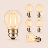 Six G45 globe LED replacement bulbs with E27 fitting and warm white filament glow on a light background