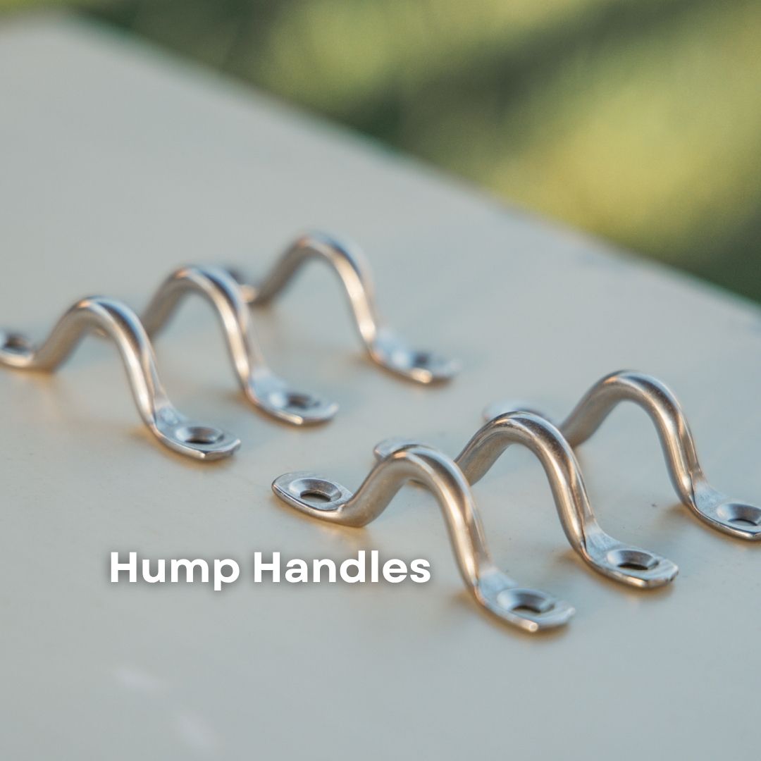 Four silver metal hump handles arranged on a light beige surface with a blurred green outdoor background. The text 'Hump Handles' is overlaid near the bottom.