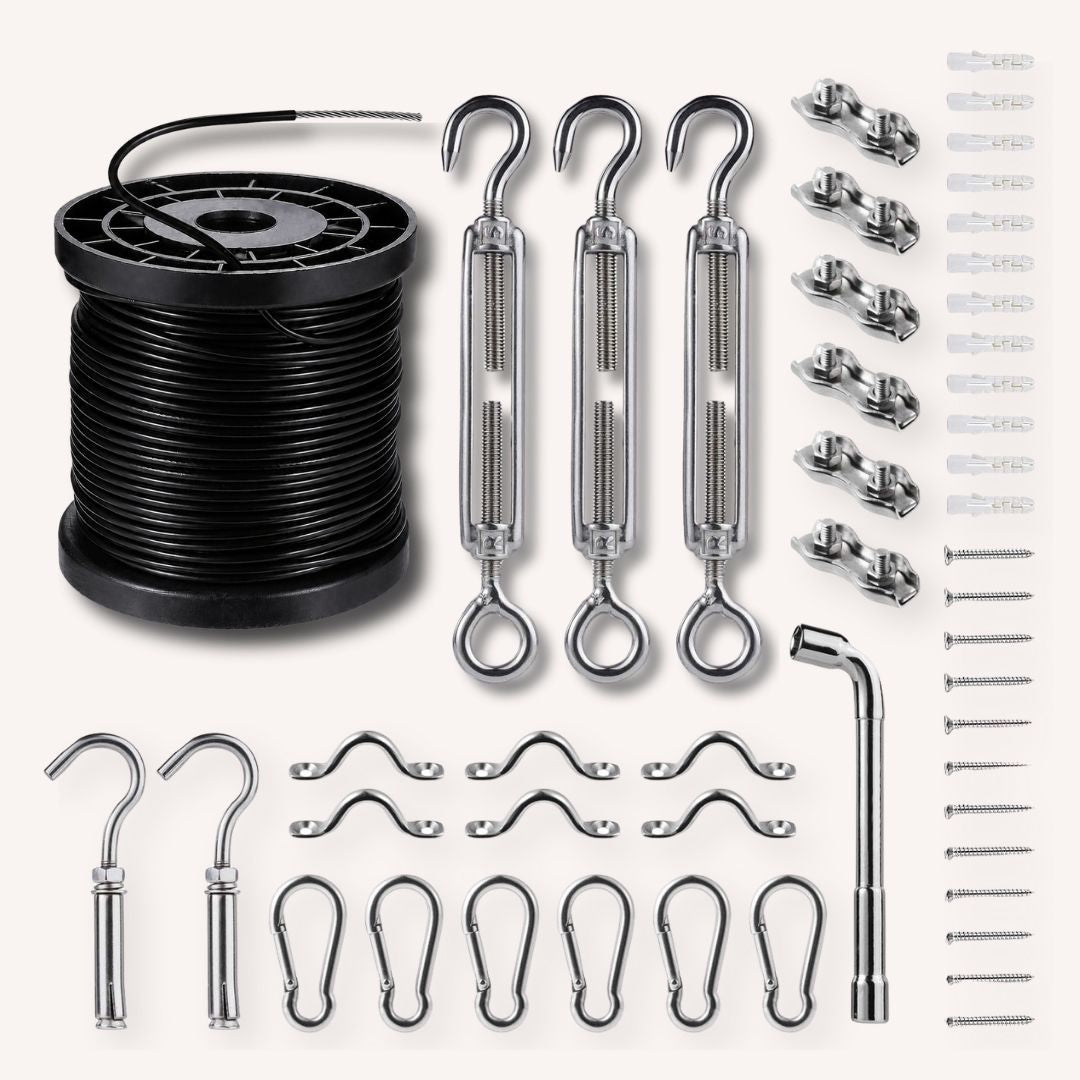 A hardware kit laid out on a light beige background, including a spool of black cable, three silver turnbuckles, multiple wall anchors, screws, hooks, and clips.